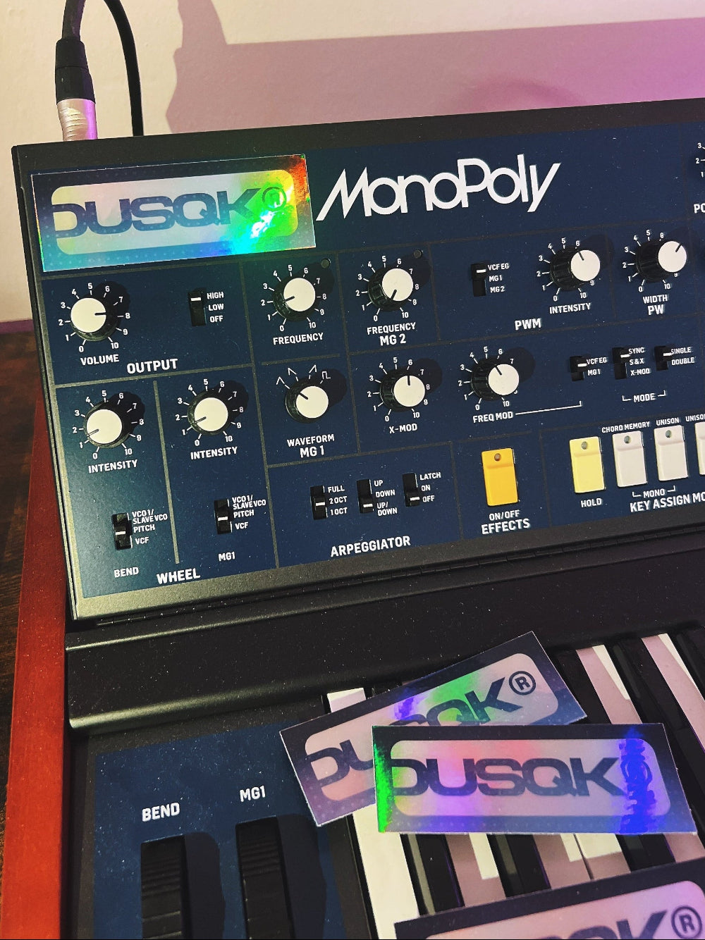 Music synthesizer with Dusqk branding on stickers and display